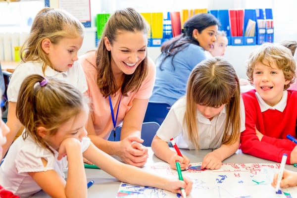 Adult supporting a group of primary pupils at a table