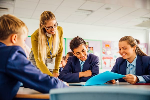Adult working with secondary pupils in a classroom